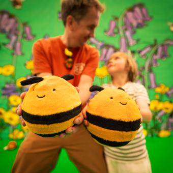 Father and son holding out bee-shaped balls